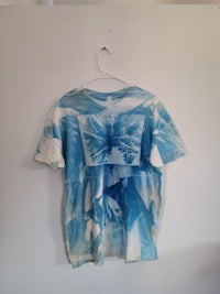 a blue tie dye t - shirt hanging on a wall